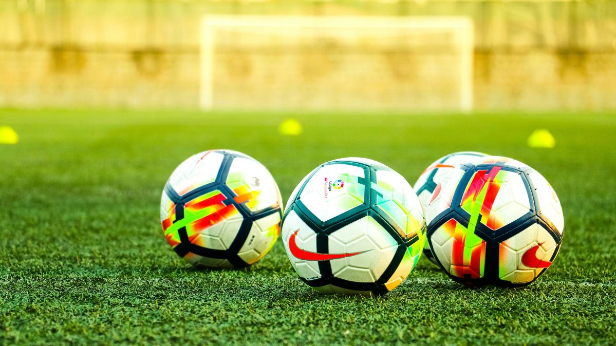 Three soccer balls in a soccer field