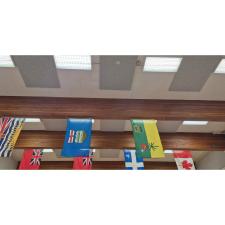 An image of a gymnasium ceiling showing fluorescent lights, flags hanging from rafters and new acoustic tiling on a ceiling.