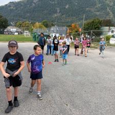 Children run across a paved schoolyard on a late summer day